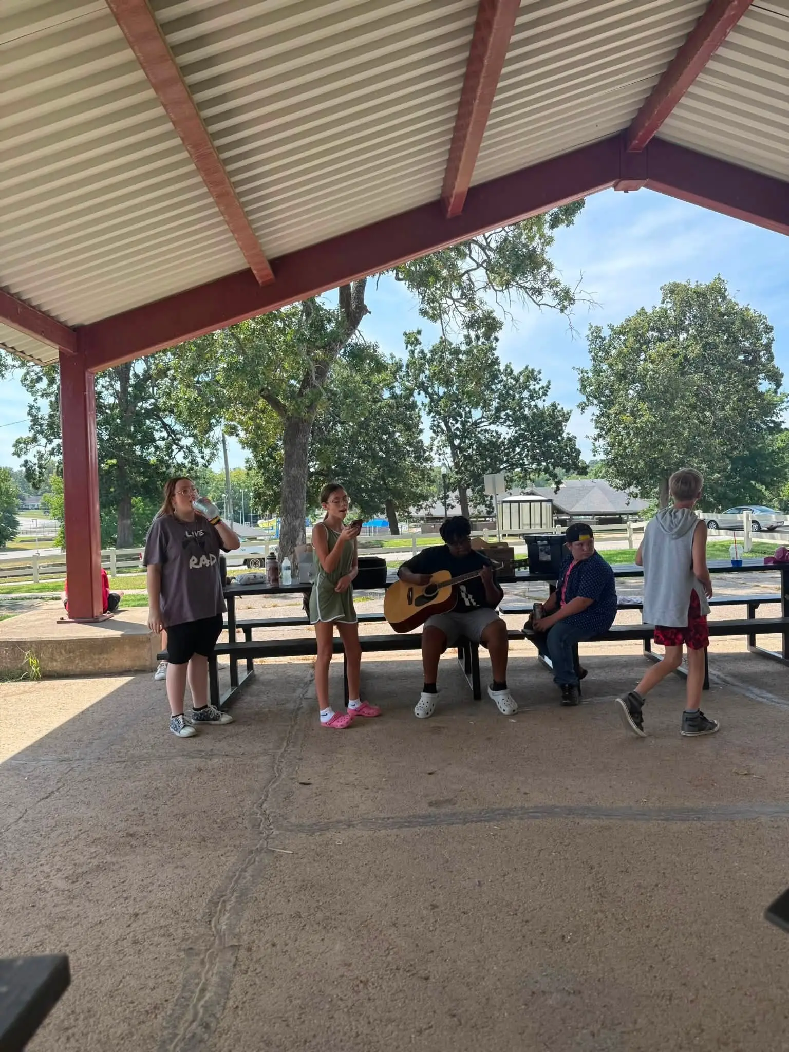 Students gathered under the pavilion around a guitar player